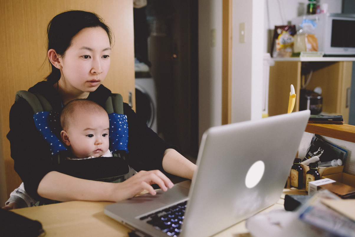 Working Mother with Laptop While Hugging Baby